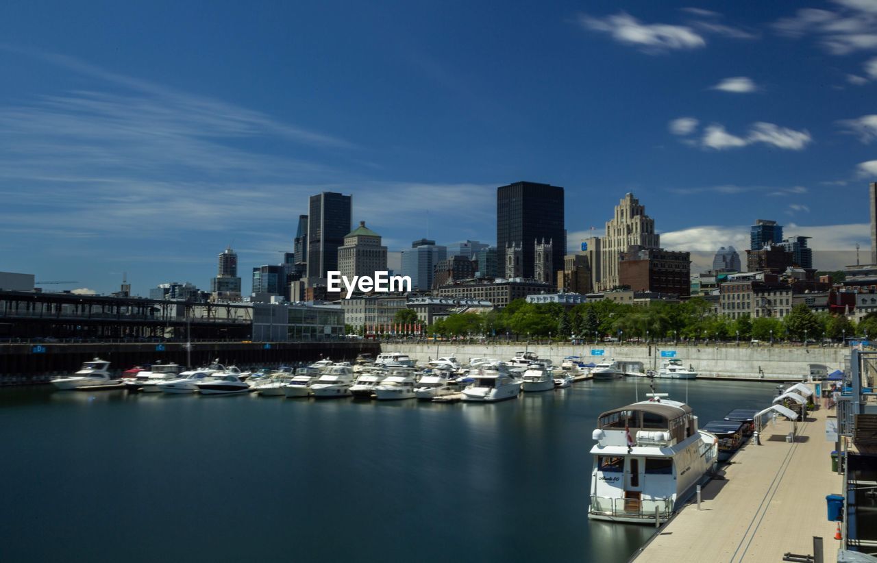 Boats moored in river by buildings against sky in city