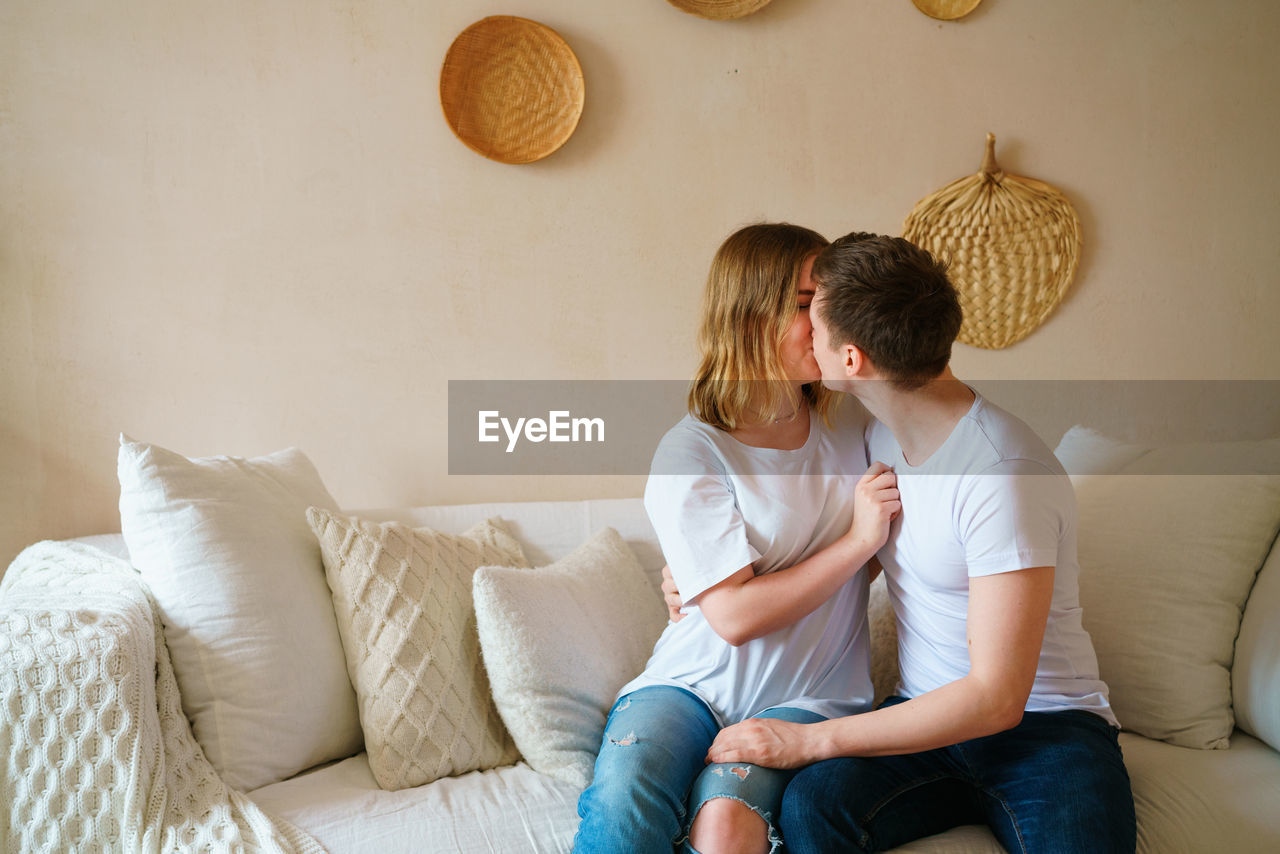 Young couple at home in casual clothes. guy and girl hug and kiss, having fun