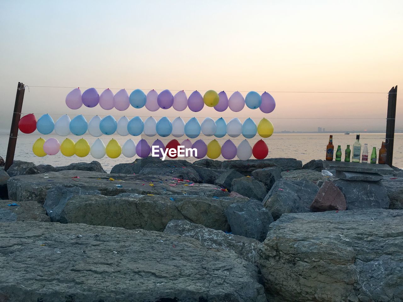 MULTI COLORED ROCKS ON SHORE AGAINST CLEAR SKY