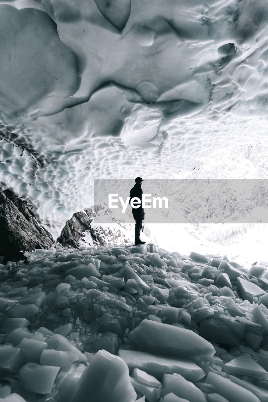 Side view of young woman standing on rock in cave