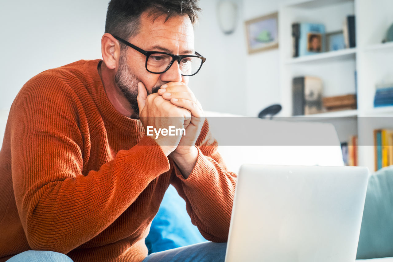 young man using laptop while sitting on sofa at home