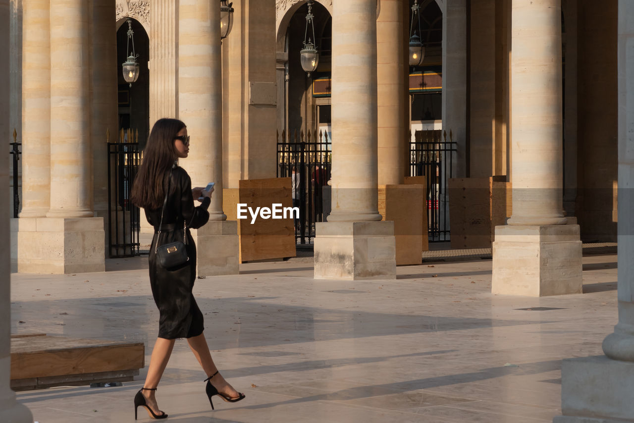 FULL LENGTH SIDE VIEW OF WOMAN WALKING AGAINST BUILDING