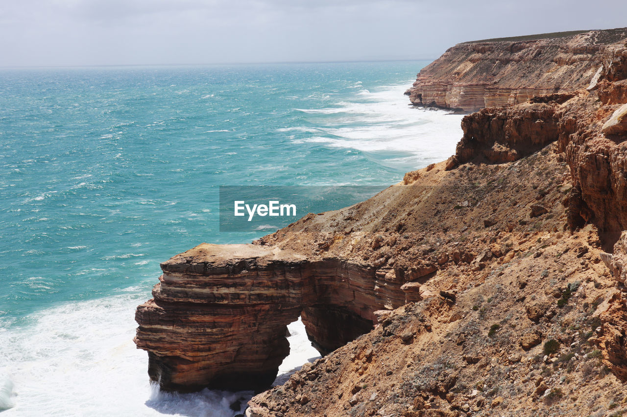 Scenic view of rock formation in sea against sky