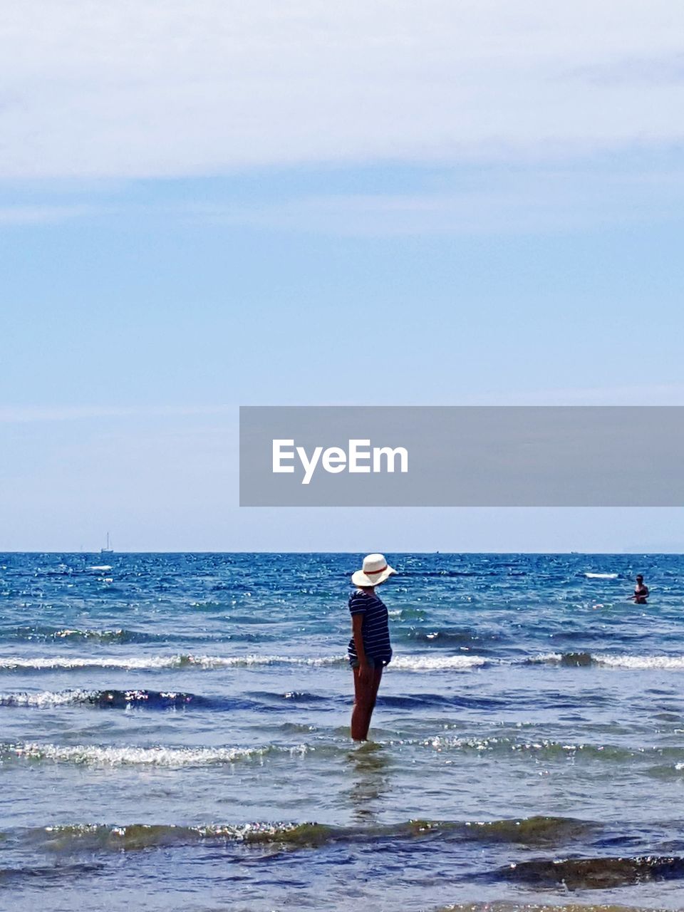 Side view of woman standing in sea against sky