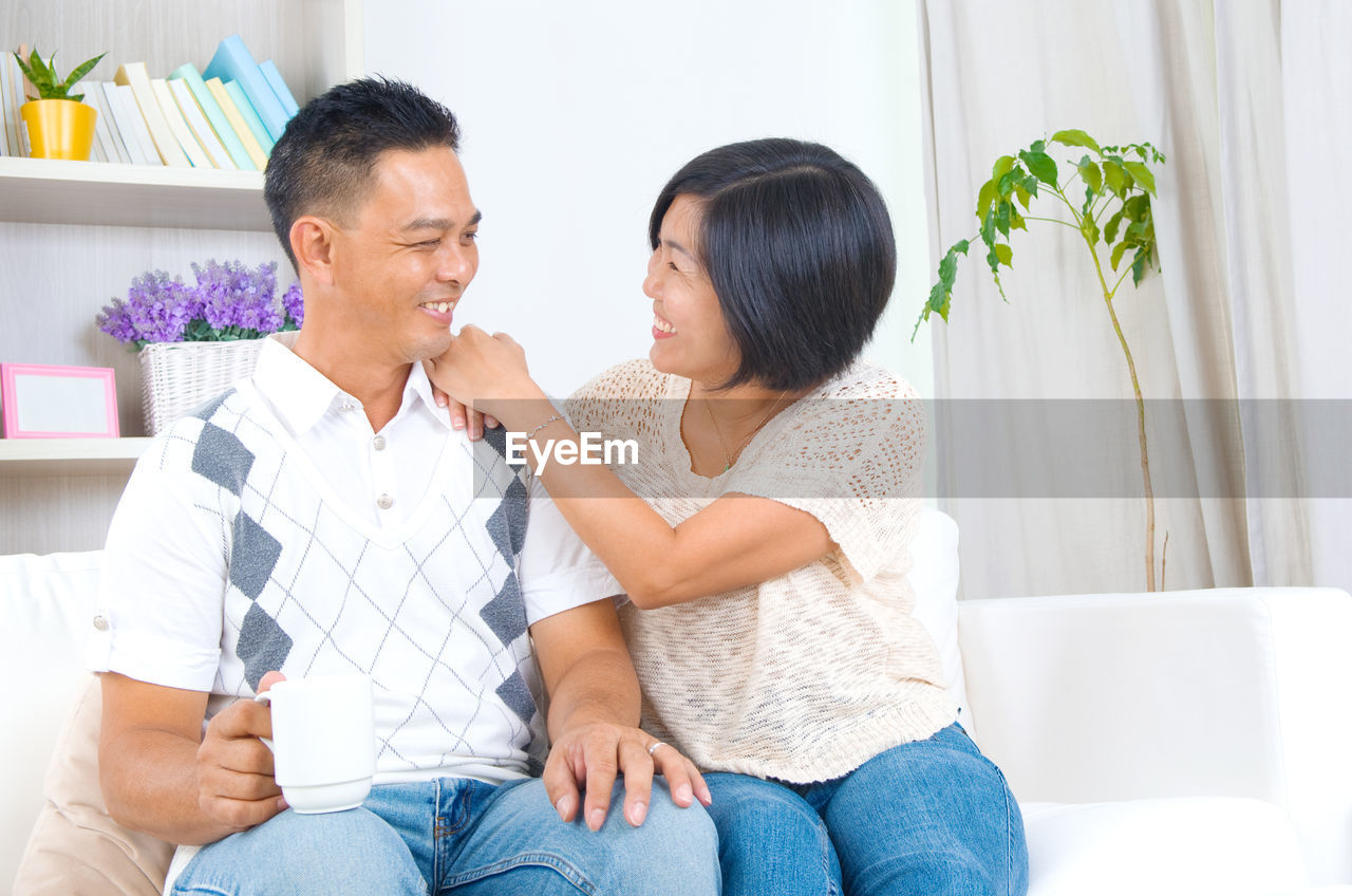 Smiling couple talking while sitting at home