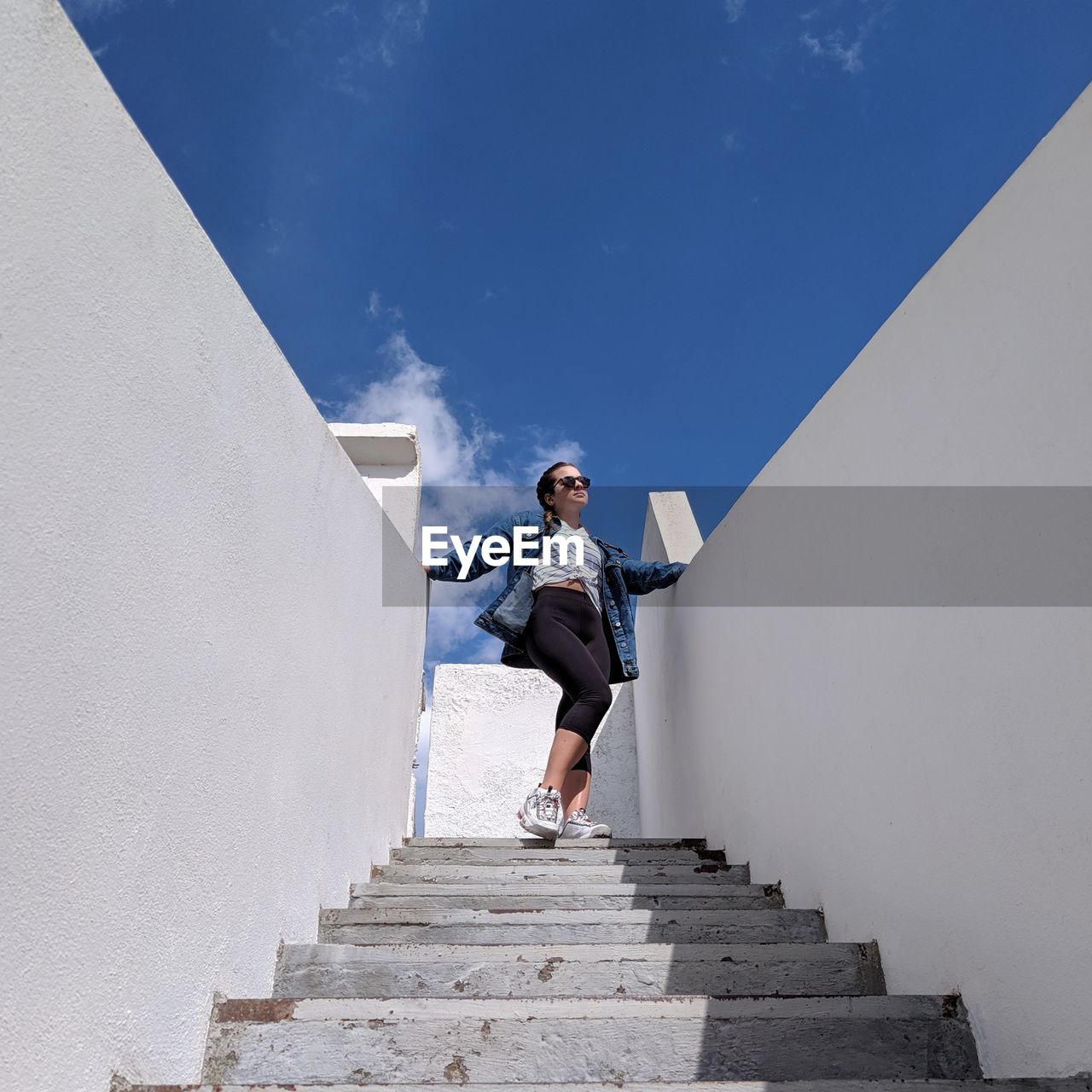 Low angle view of woman standing on staircase against sky