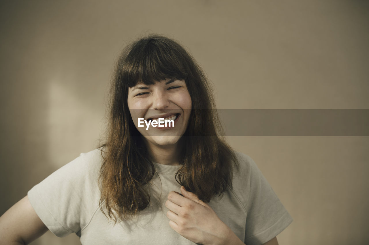 Cheerful young woman against beige wall