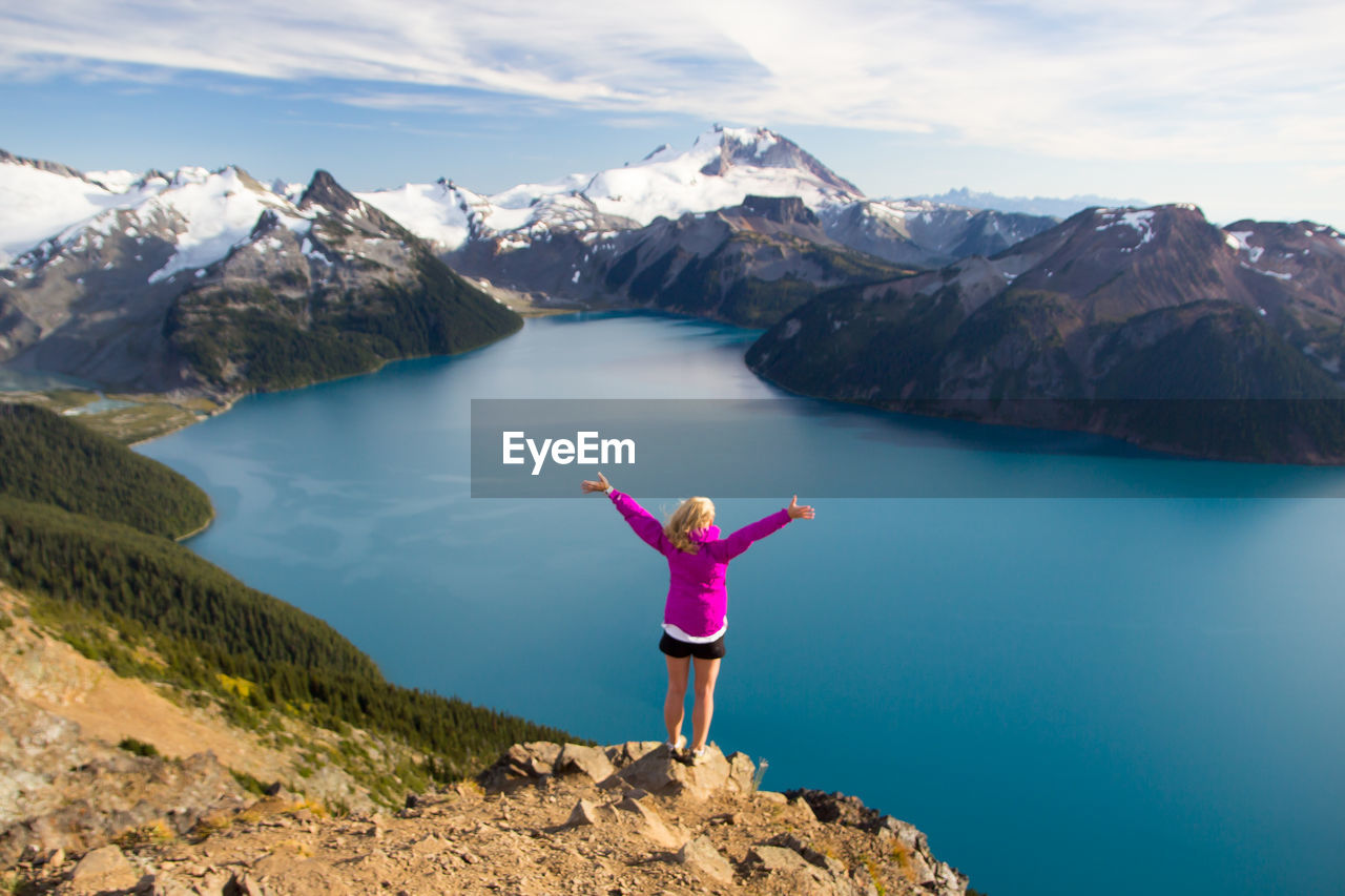 Rear view of woman standing on mountain against river
