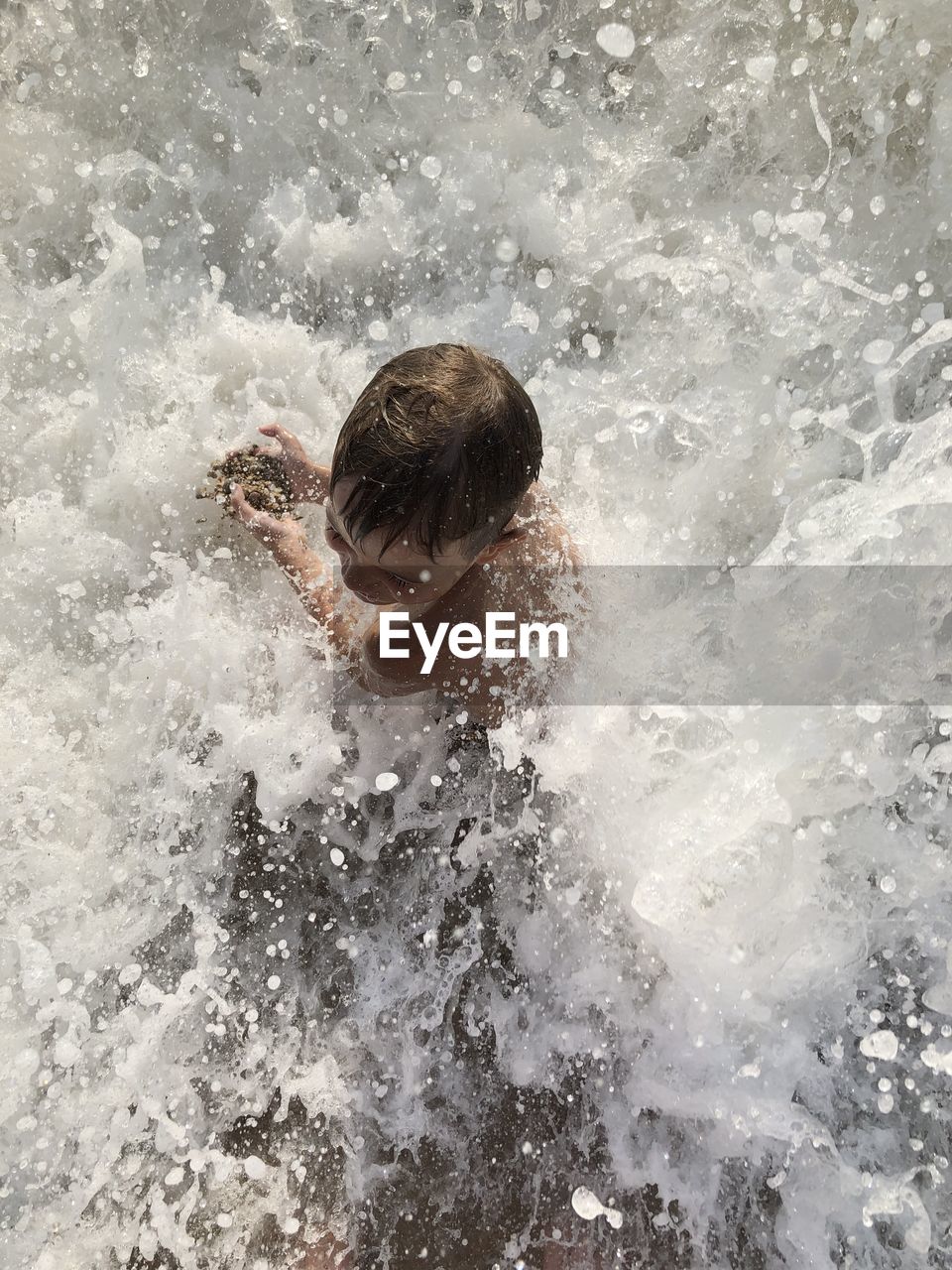 High angle view of shirtless boy in sea