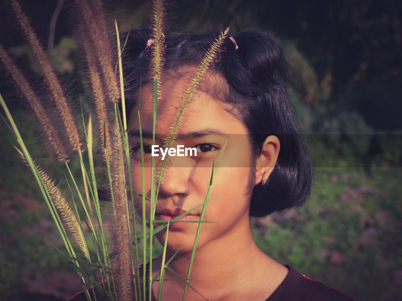 Close-up portrait of serious girl holding plants