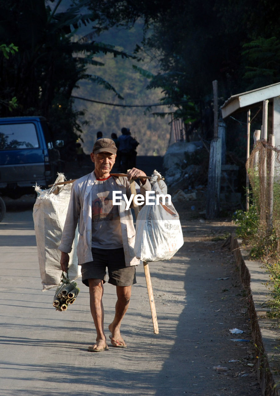 REAR VIEW OF MAN WALKING ON FOOTPATH