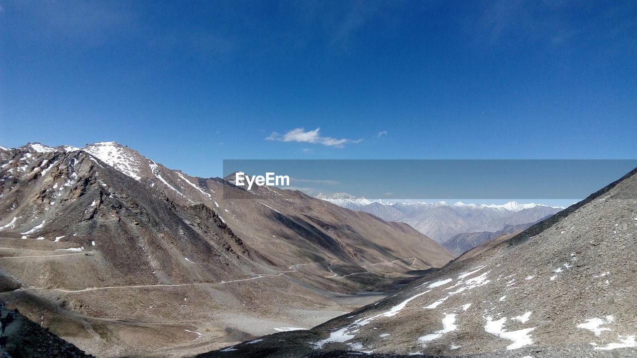 Scenic view of snowcapped mountains against blue sky