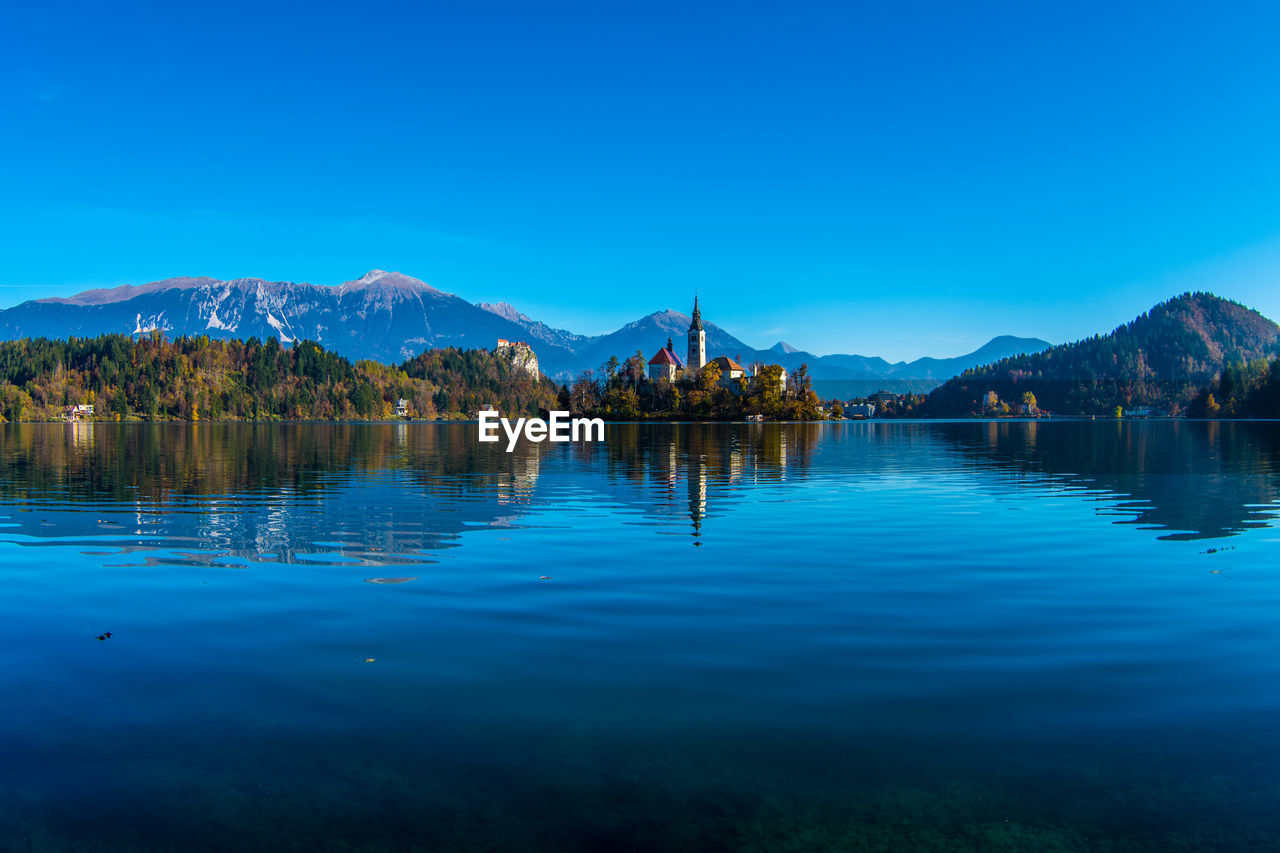 Scenic view of lake by mountains against blue sky