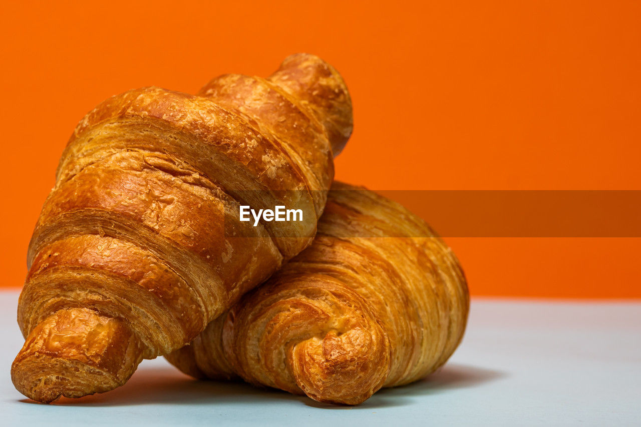 croissant, food, food and drink, french food, viennoiserie, baked, studio shot, freshness, no people, colored background, dessert, bread, produce, still life, indoors, brown, close-up, healthy eating, loaf of bread, wellbeing, table, gold