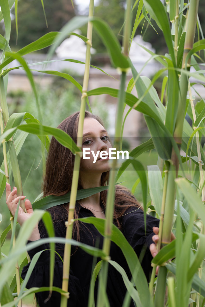 Portrait of young woman lying on plant