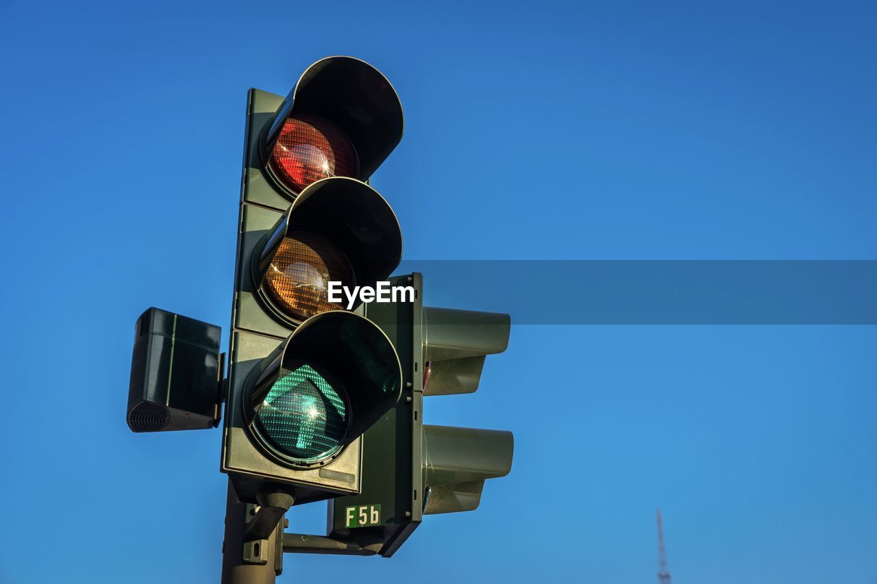 Low angle view of road signal against clear blue sky