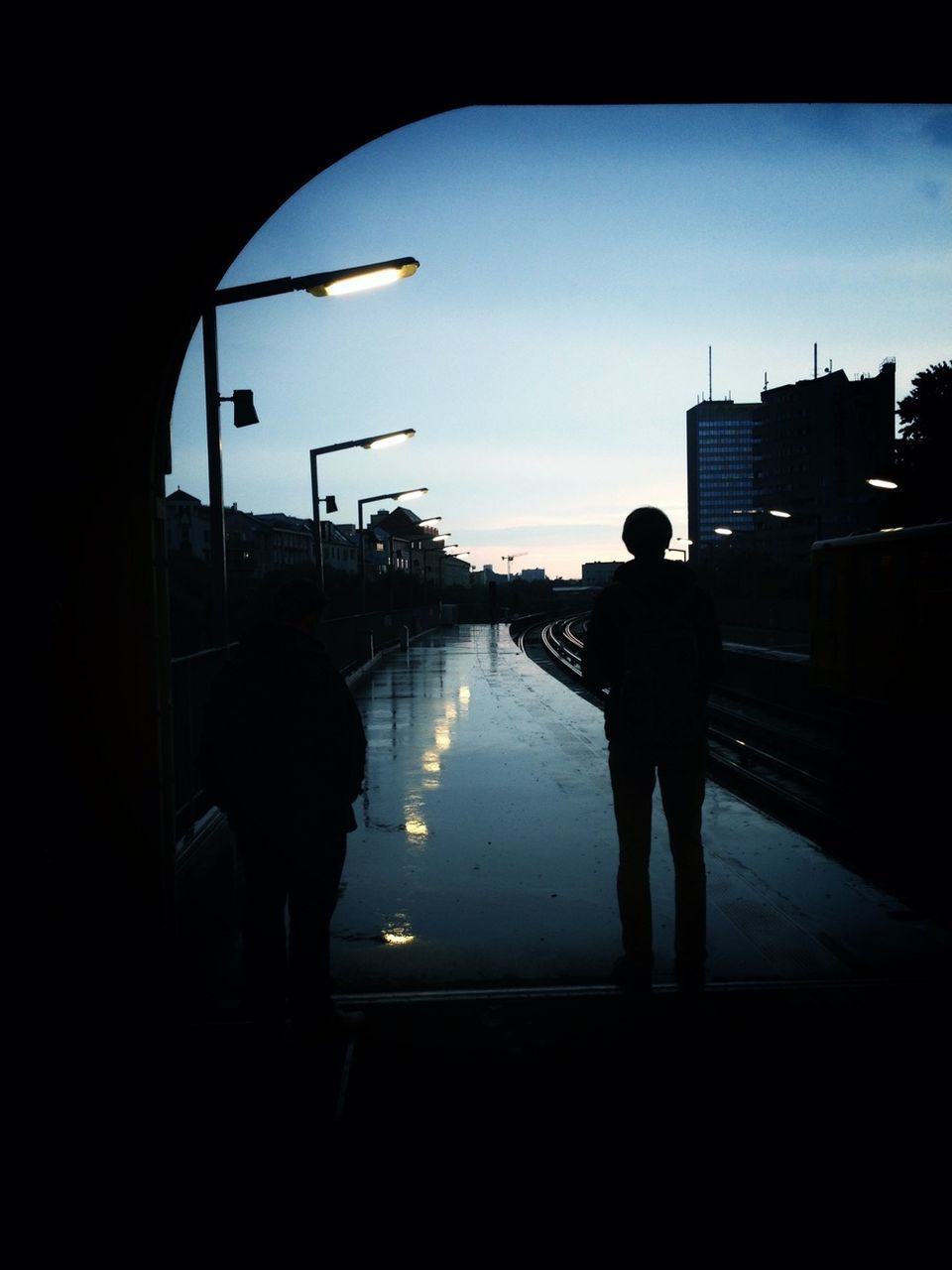Silhouette of two person standing on railway station platform