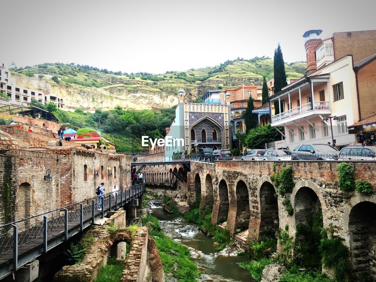 ARCH BRIDGE AMIDST BUILDINGS AGAINST SKY