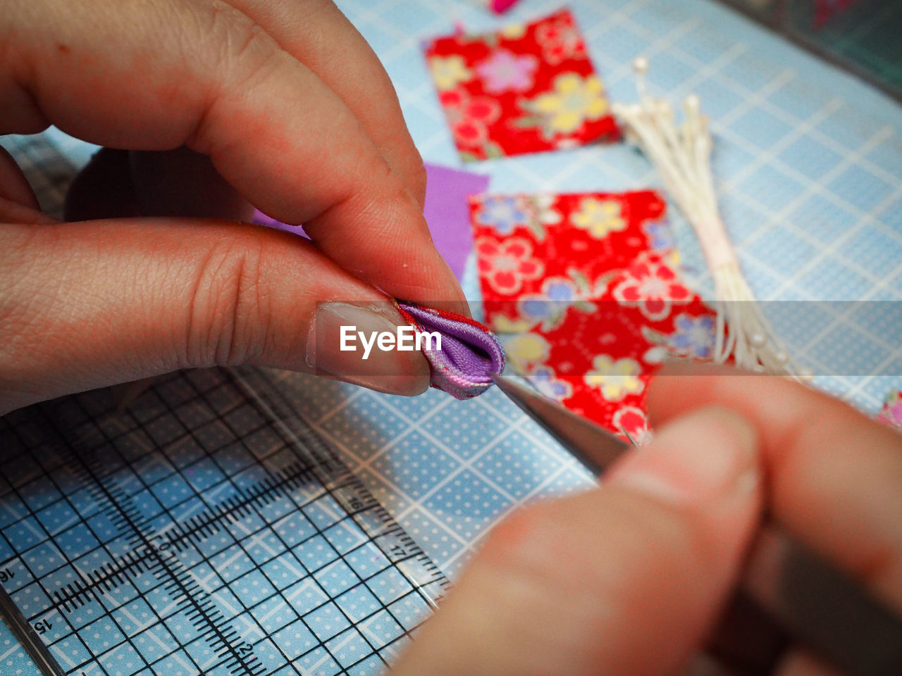 Cropped hands making fabric artwork at table