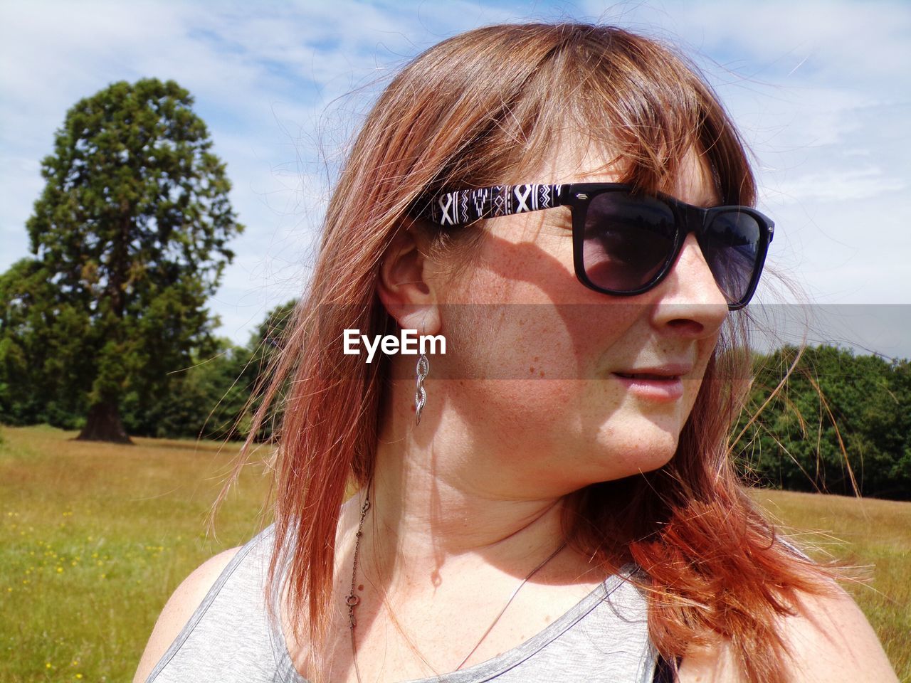 Close-up of woman wearing sunglasses looking away on field