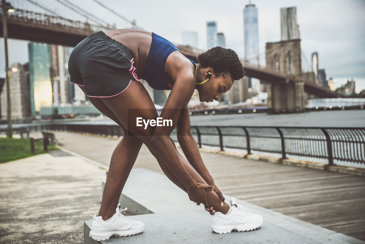 Woman exercising on bridge in city