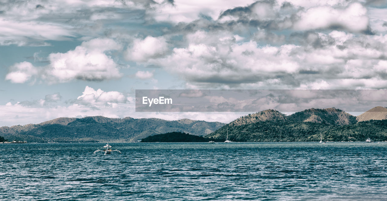 SCENIC VIEW OF SEA AGAINST MOUNTAINS