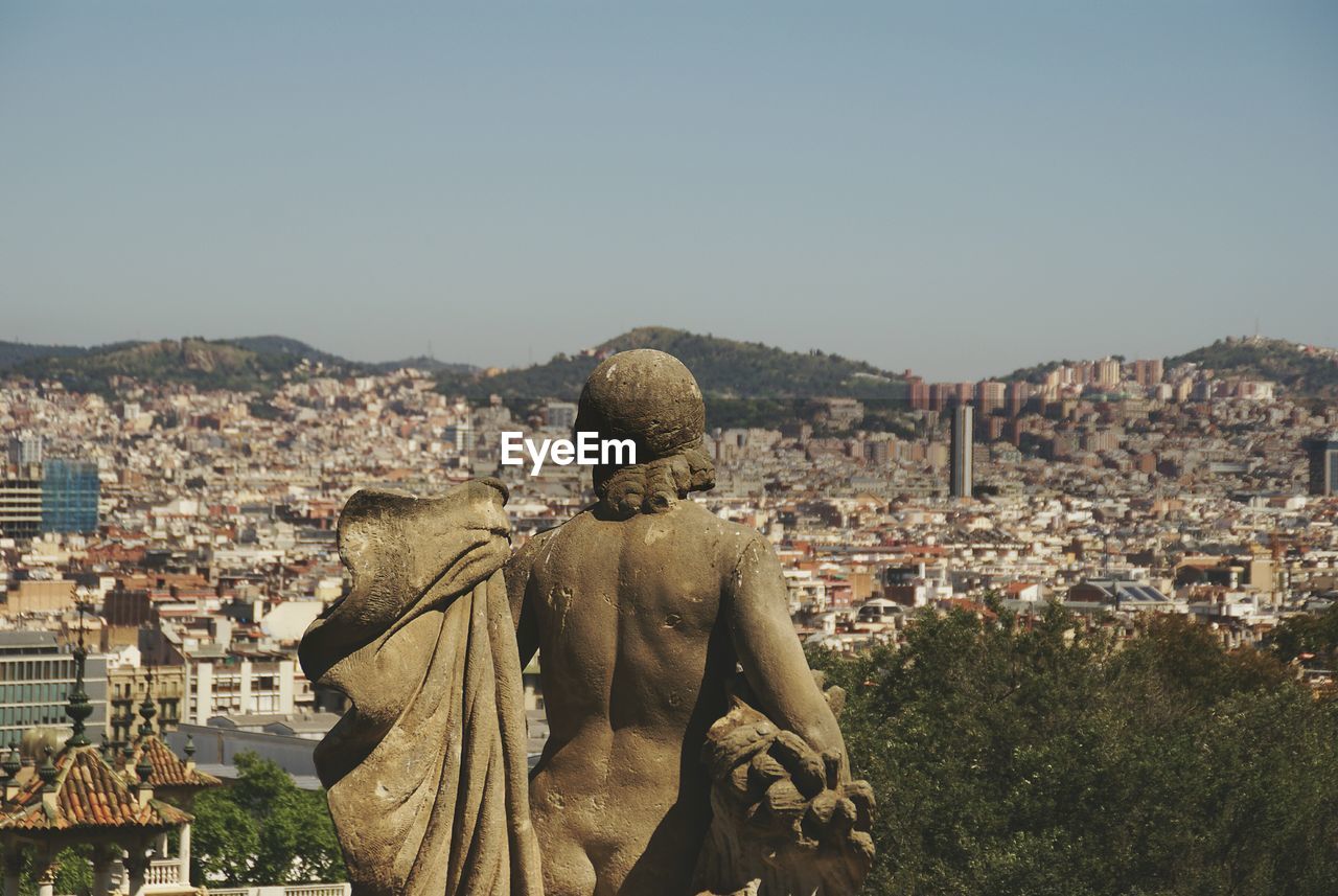 Naked statue overlooking cityscape