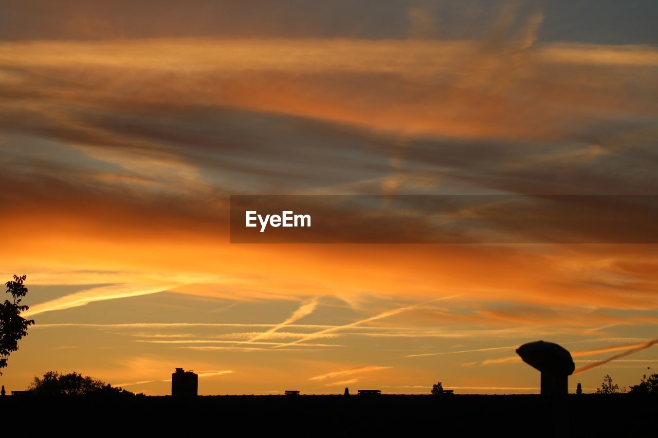 Silhouette landscape against dramatic sky during sunset