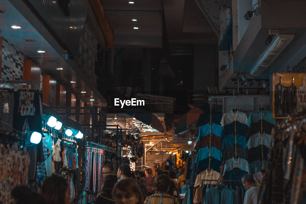PEOPLE IN ILLUMINATED MARKET AT NIGHT IN CITY
