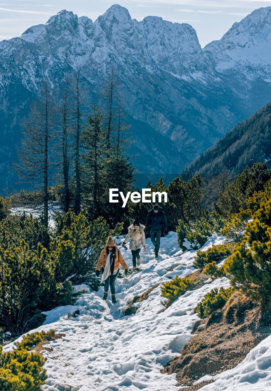 Group of friends hiking on snowy path in mountains