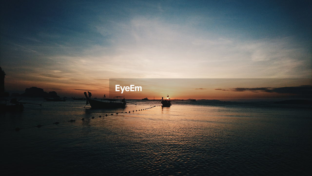 Silhouette boat moored on sea against sky during sunset