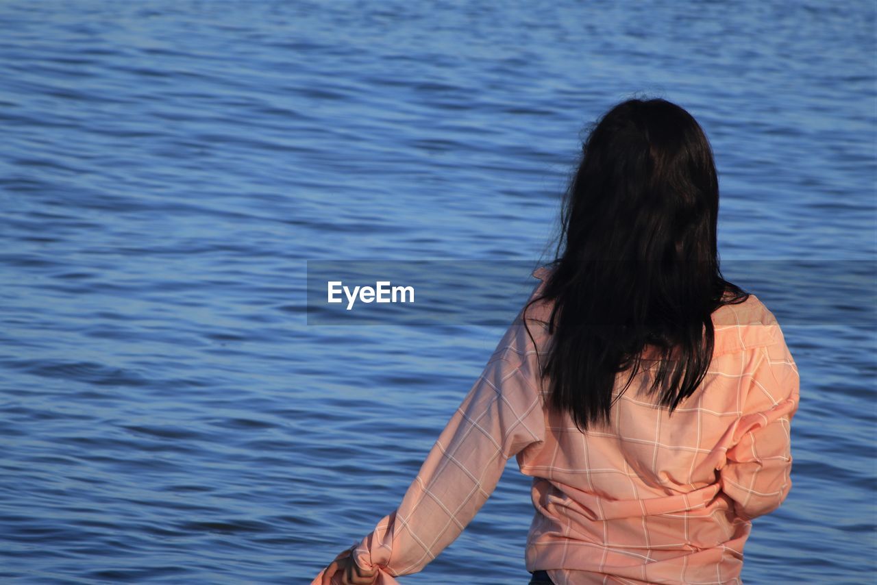 Rear view of woman standing in sea