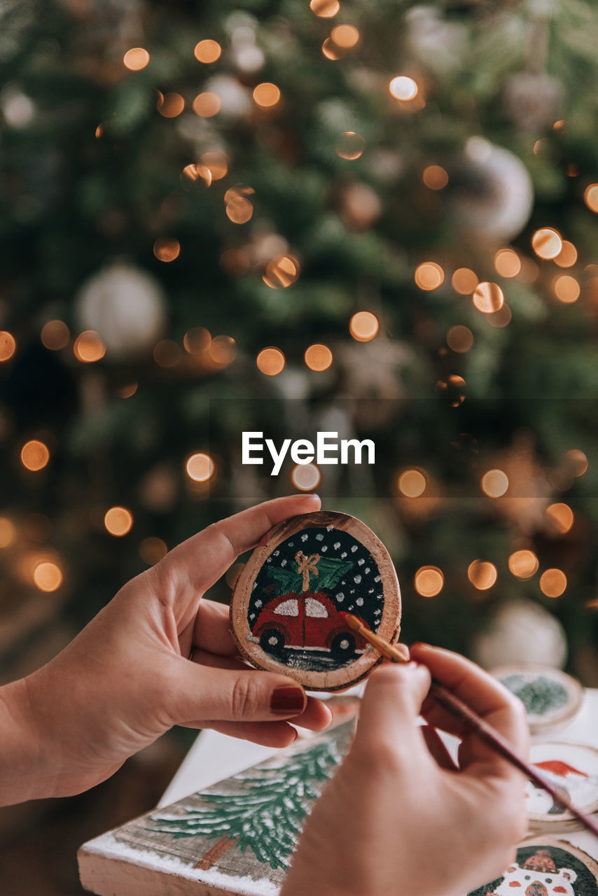 Female hand making diy christmas ornament, painting on a wooden slice