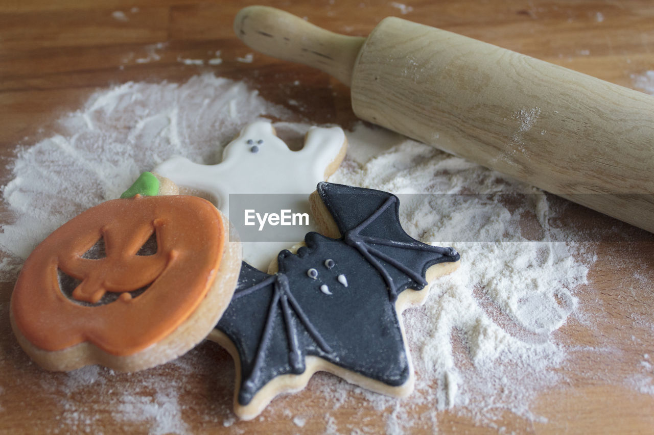 Halloween cookies, flour and rolling pin on wooden table