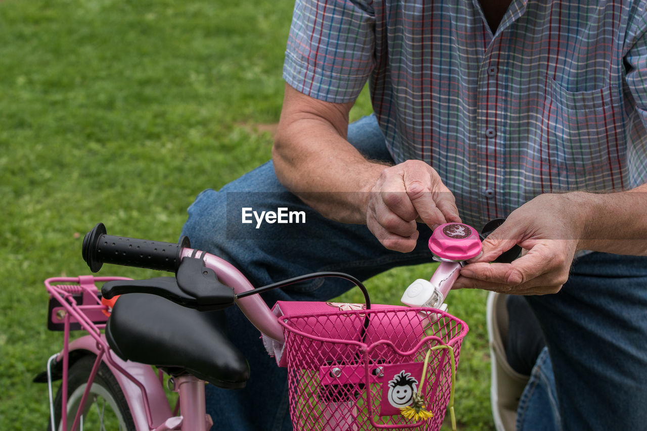 Midsection of man repairing bicycle on field