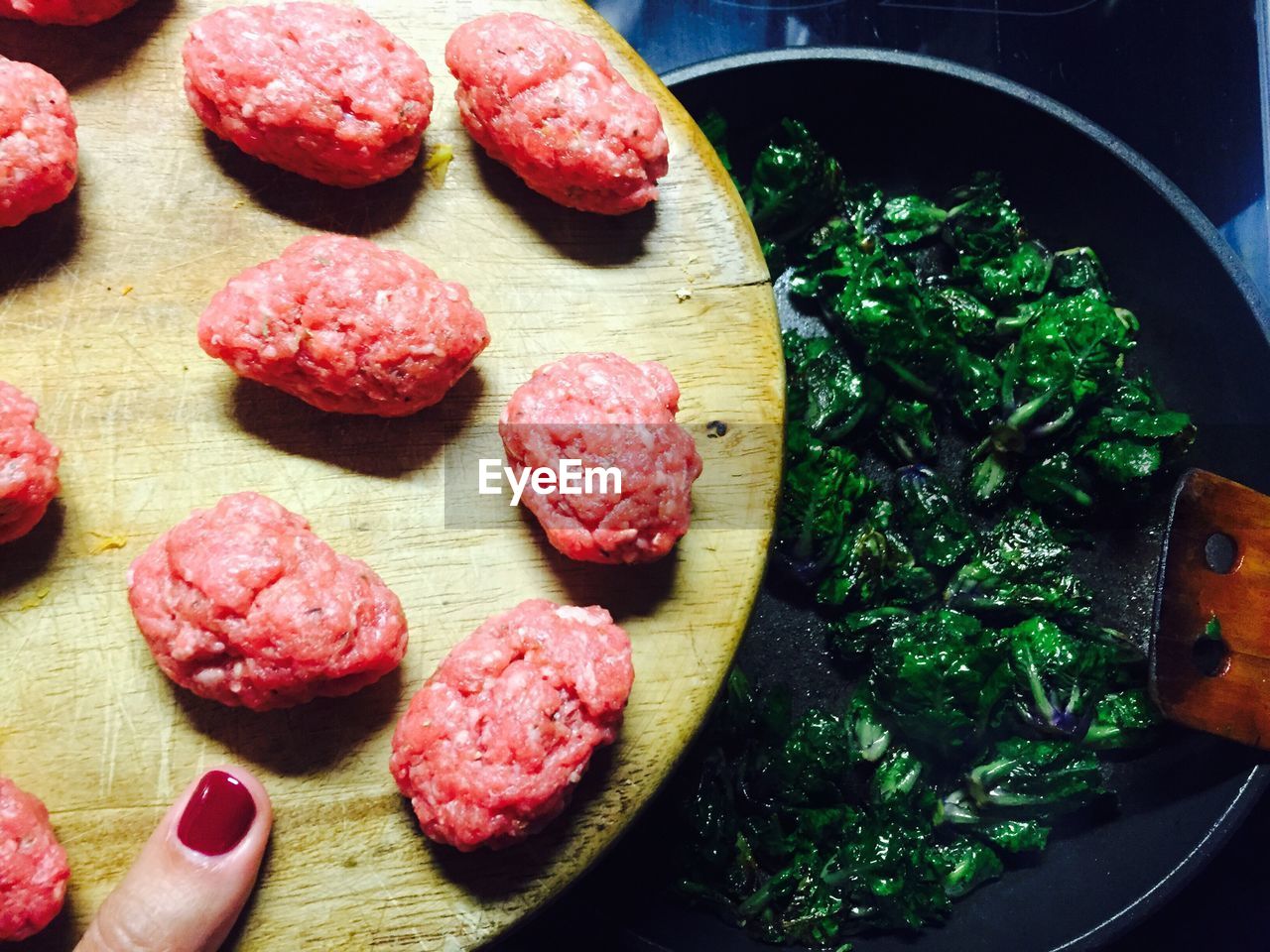 Cropped image of woman holding meat on cutting board while preparing food