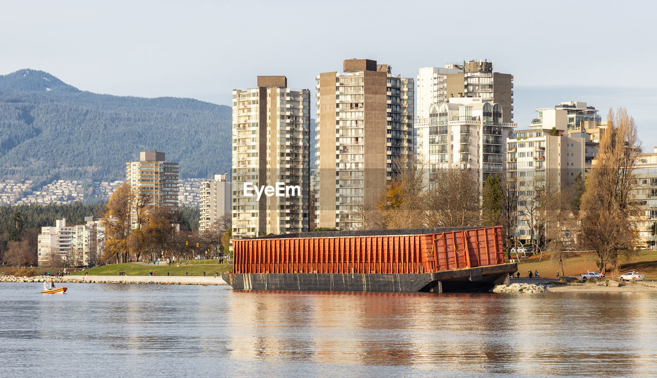 VIEW OF BUILDINGS BY RIVER AGAINST SKY IN CITY