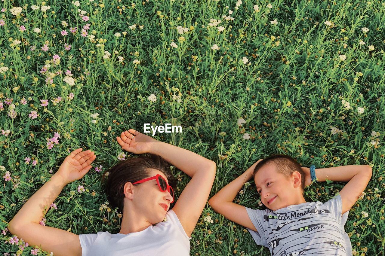 Directly above shot of mother with son lying on grassy land