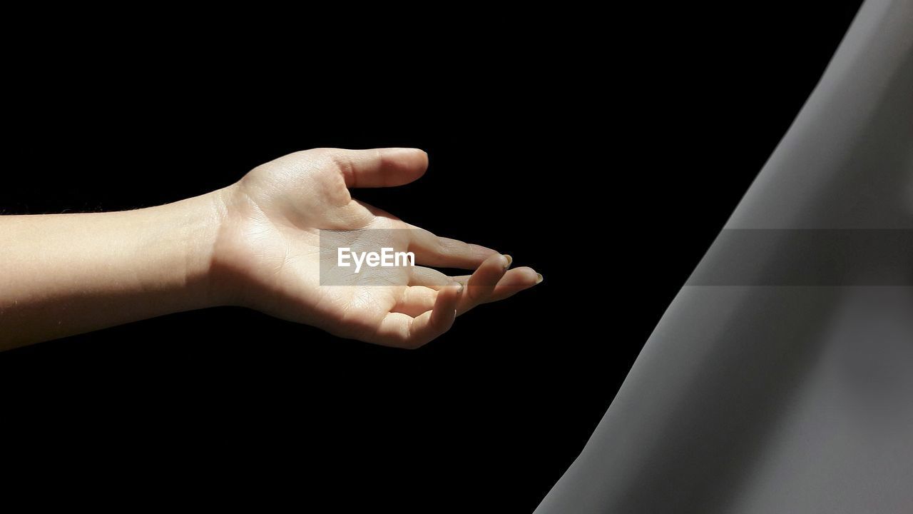 Cropped hand of woman gesturing against colored background