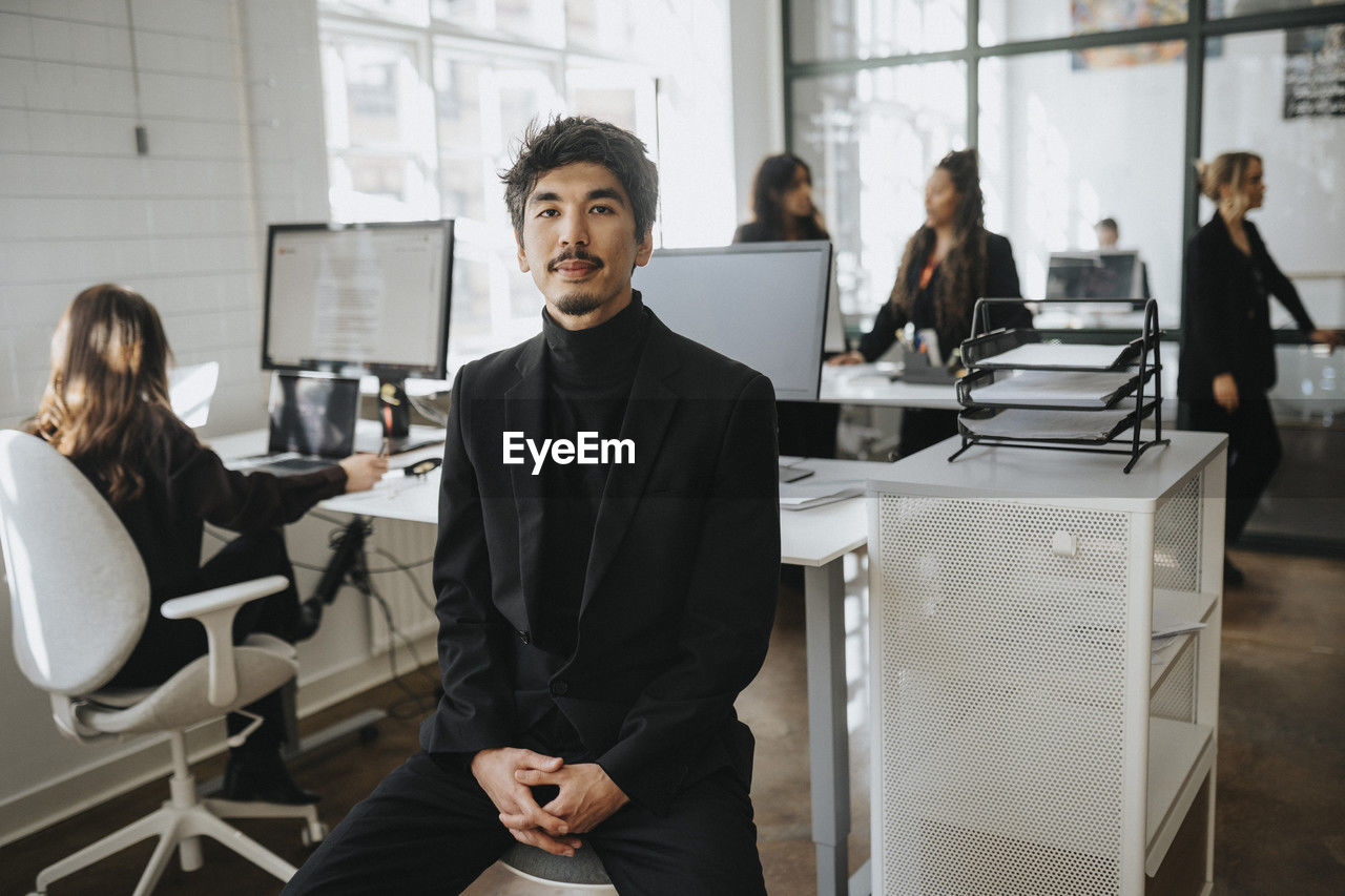 Portrait of businessman sitting with hands clasped sitting at office