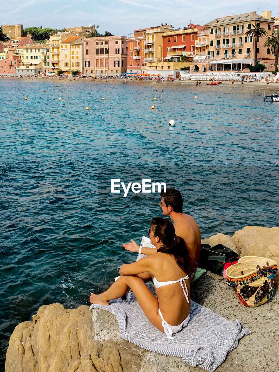 Friends sitting on seashore against buildings