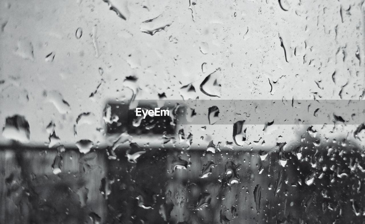 CLOSE-UP OF RAINDROPS ON GLASS WINDOW