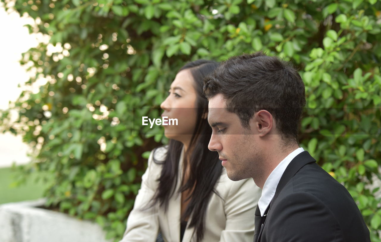 PORTRAIT OF FRIENDS LOOKING AWAY AGAINST TREES