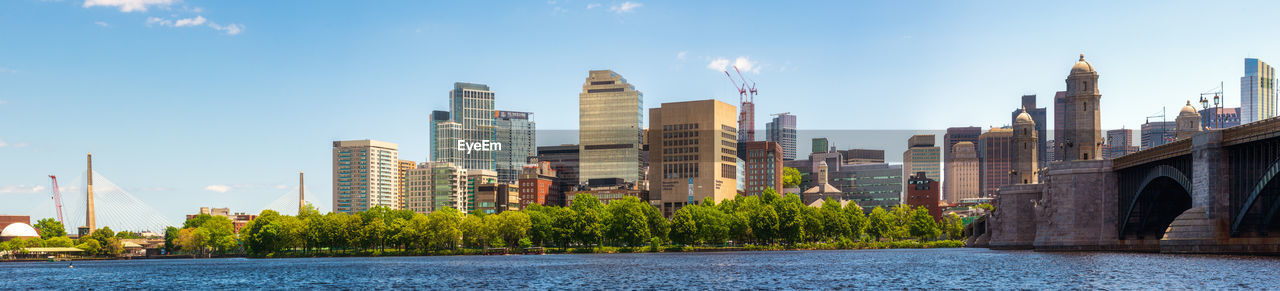 Modern buildings by river against sky in city