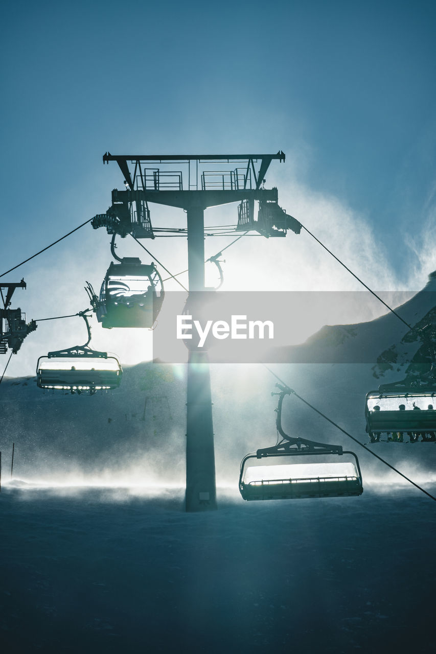 People skiing underneath ski lift in stormy conditions, kitzsteinhorn ski resort, austria