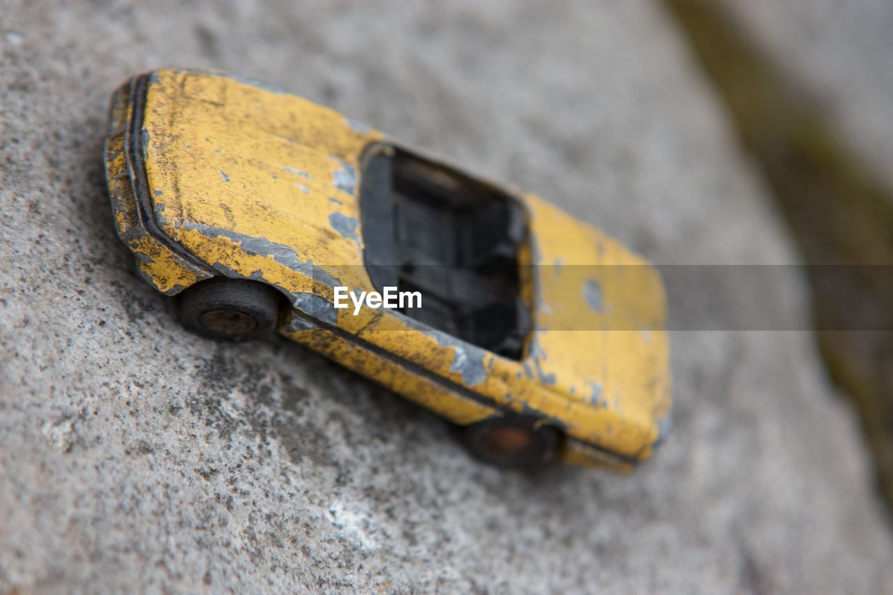 HIGH ANGLE VIEW OF RUSTY TOY CAR ON WOOD