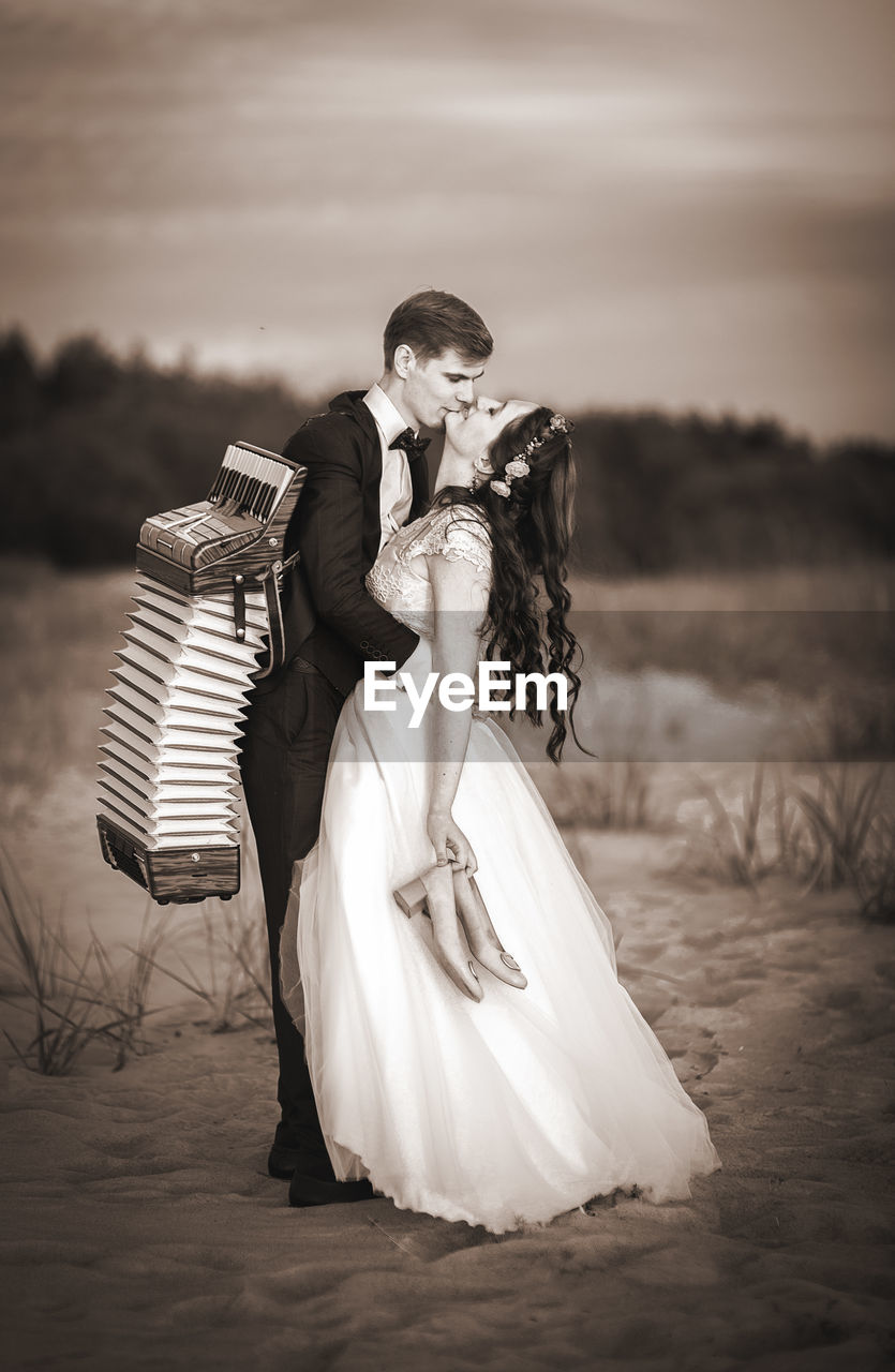 Couple kissing at beach against sky