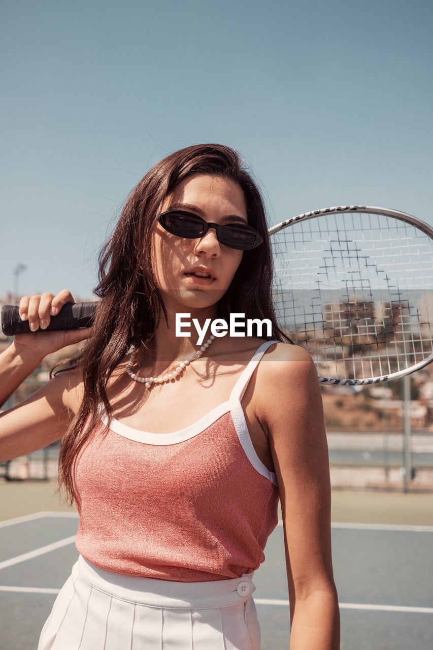 YOUNG WOMAN WEARING SUNGLASSES AGAINST SKY