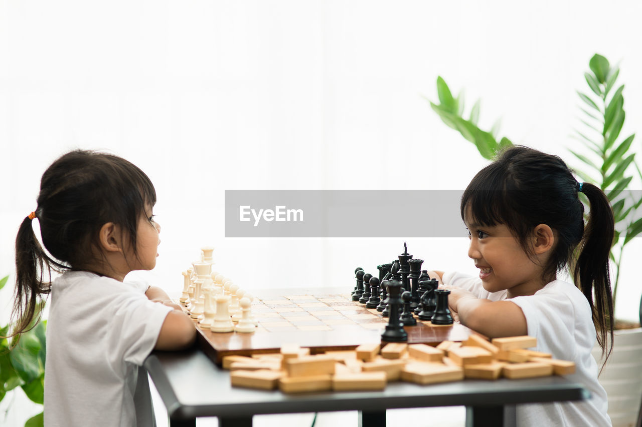 Cute sisters playing chess at home