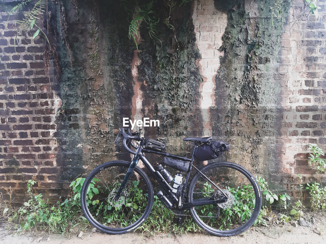 BICYCLE PARKED AGAINST BRICK WALL